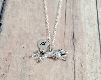 May include: A silver necklace with a charm of a jumping squirrel and a small round charm with the letter "D" on it.