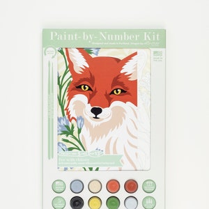 Paint by number kit for adults featuring a red fox bust and blue chicory stalks. The craft kit is in its eco-friendly packaging from Elle Crée showing 8 acrylic paints and 2 vegan paintbrushes.