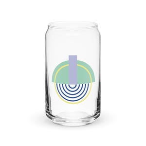May include: A clear glass can with a geometric design in shades of green, blue, and yellow. The design features a half circle with a striped pattern and a smaller rectangle in the center.