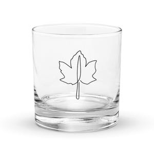 Puede incluir: Un vaso transparente de vidrio con un dibujo simple de una hoja de arce en la parte delantera.
