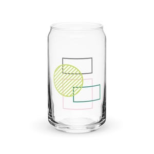 May include: A clear glass can-shaped drinking glass with a colorful geometric design. The design includes a lime green circle with diagonal lines, a pink rectangle, a teal rectangle, and a gray rectangle.