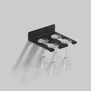 May include: Black metal wall-mounted wine glass rack with four clear glass goblets hanging from it.