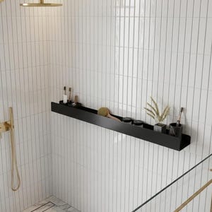 May include: A black metal shower shelf on a white tiled wall, holding toiletries. The shelf contains toothbrushes, small jars, a brush, and decorative plants. A gold shower head and wand are visible.