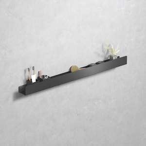 May include: A black metal wall-mounted shelf with various bathroom accessories. The shelf holds toothbrushes, a comb, a brush, small containers, and a small potted plant. The shelf is mounted on a light gray wall.