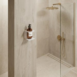 Pode incluir: Uma casa de banho moderna com um chuveiro de vidro e acessórios dourados. Uma garrafa castanha com dispensador de bomba está numa prateleira branca. O chuveiro é circular e as paredes são revestidas a azulejos.