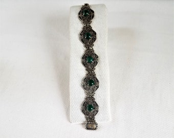 May include: A silver bracelet with green stones set in filigree designs.