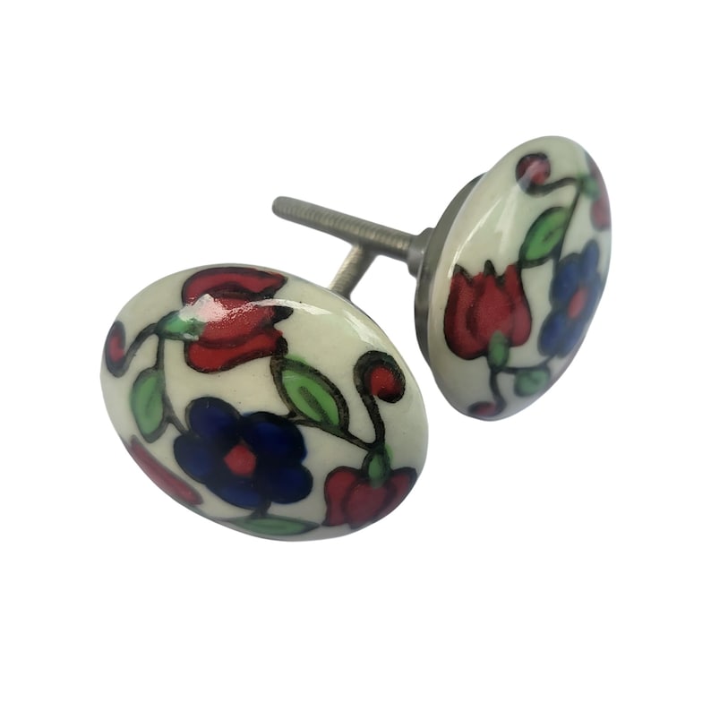 May include: Two ceramic cabinet knobs with a floral design. The knobs are oval-shaped with a cream-colored base and feature red, blue, and green floral patterns. The hardware is silver-colored.