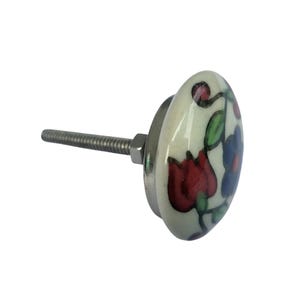 May include: An oval ceramic cabinet knob with a floral design. The knob features a cream-colored base with red, blue, and green floral patterns. It has a metal screw and nut for attachment. A decorative accent for furniture.