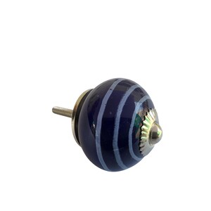 May include: A navy blue ceramic cabinet knob with light blue stripes. The knob has a silver-coloured metal base and screw. This decorative hardware is suitable for drawers, cabinets, and furniture.