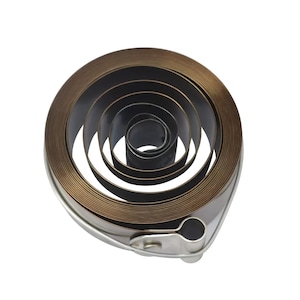 May include: A coiled metal spring with multiple layers, designed for use in a mechanical device. The spring is made of a thin, flexible metal and has a silver-colored finish.