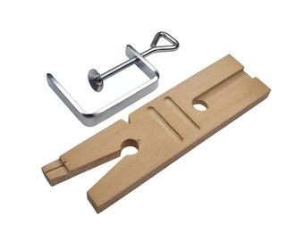 May include: A silver metal clamp with a wooden base. The base has a slot for holding a ring or other jewelry while it is being worked on.