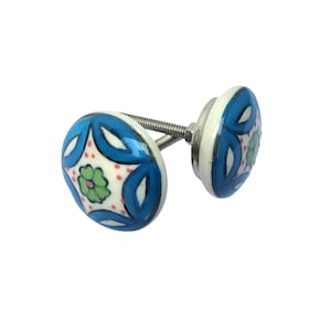 May include: Two ceramic cabinet knobs with a floral design. The knobs feature a white base with a blue, green, and red floral pattern. The knobs are connected by a metal screw.
