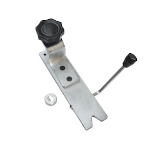 May include: A silver-colored metal tool with a black knob and handle. The tool has a rectangular base with a forked end and a small, round, silver-colored piece.