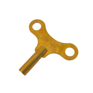May include: A gold-colored metal clock winding key with a T-shaped handle and a long, thin shaft. The key has the text "5 25 NO 12" engraved on the handle.