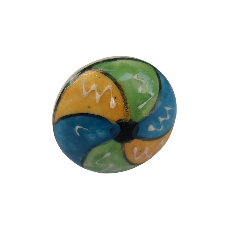 Pode incluir: Um puxador decorativo redondo e colorido com acabamento brilhante. O puxador apresenta um design segmentado com sec&ccedil;&otilde;es azuis, verdes e amarelas, acentuadas com ziguezagues brancos. O centro &eacute; preto. Este puxador &eacute; provavelmente para m&oacute;veis.