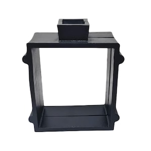 May include: A black, square candle holder with a rectangular base and a small square cup on top. The candle holder has a decorative, rounded design on the sides.