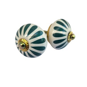 May include: Two decorative ceramic cabinet knobs. Each knob is white with a teal petal design and gold-colored hardware. The knobs are round and have a gold-colored base.
