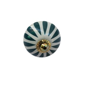 May include: A round, decorative cabinet knob with a white base and dark teal, fan-like stripes. The knob features a gold-colored metal base and a central screw. This hardware is suitable for drawers and cabinets.
