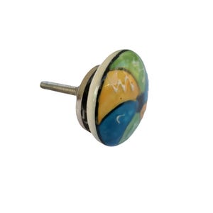 Pode incluir: Puxador de arm&aacute;rio decorativo em cer&acirc;mica com parafuso de metal. O puxador apresenta um design circular com segmentos azuis, verdes, amarelos e brancos. Um toque colorido para m&oacute;veis.