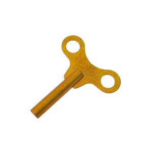 May include: A gold-colored metal wind-up key with a T-shaped handle. The handle has two holes and the text "2 1/2" NO. 0" is engraved on the key.