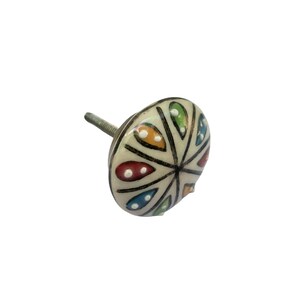 May include: A decorative ceramic cabinet knob with a cream-colored base. The knob features a colorful, symmetrical design with red, blue, yellow, and green accents. The knob has a metal screw for attachment.