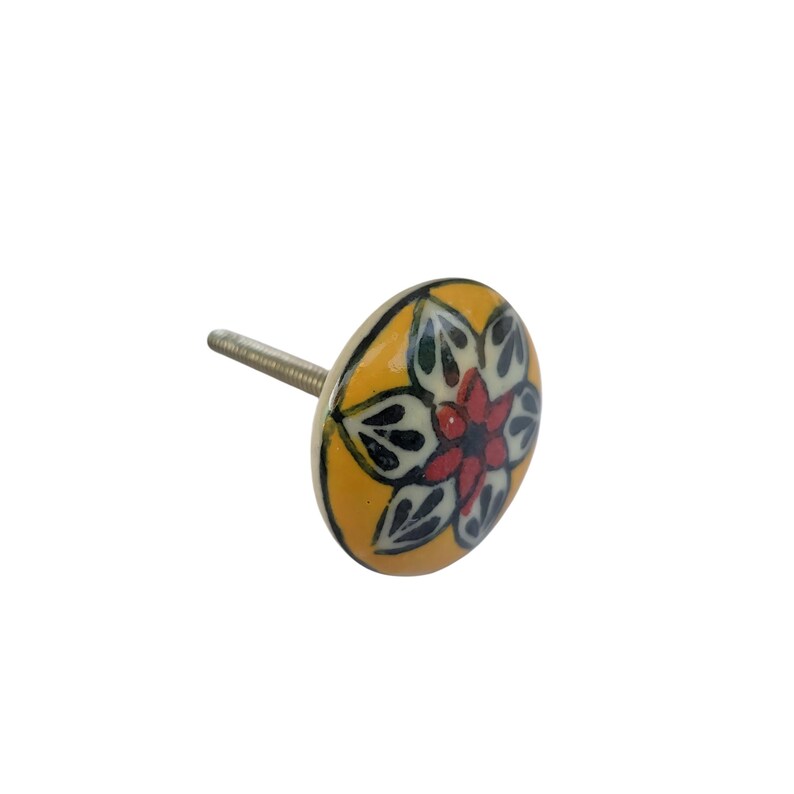 Op de afbeelding: Een decoratieve kastknop met een bloemmotief. De knop heeft een gele achtergrond met een rood, wit en zwart bloemmotief. De knop heeft een metalen schroef voor installatie.