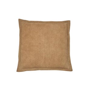 May include: A tan suede pillow with a stitched edge.