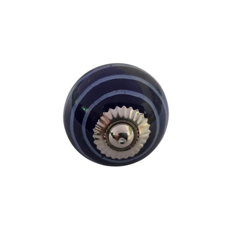 May include: A navy blue ceramic cabinet knob with a silver-coloured base and a small, clear gem in the centre. The knob has a series of light blue horizontal stripes. Decorative hardware for furniture.