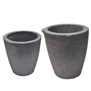 May include: Two gray, cone-shaped crucibles with textured surfaces. One crucible has a spout. The crucibles are made of a dark gray material and are set against a white background. They are used for melting metals.