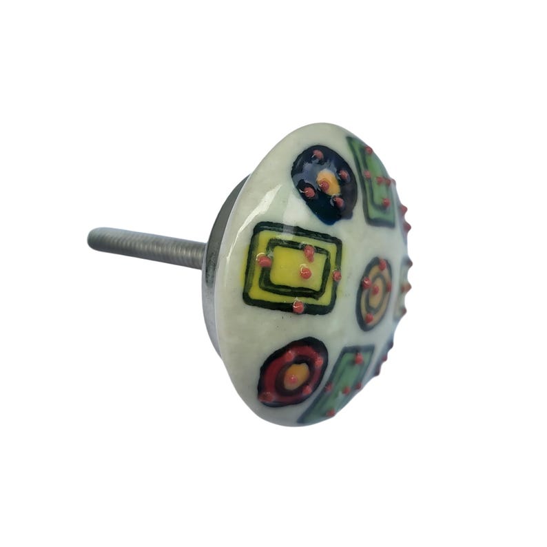 Peut inclure: Bouton de meuble d&eacute;coratif en c&eacute;ramique avec une base blanche. Le bouton pr&eacute;sente un motif abstrait color&eacute; de carr&eacute;s, de cercles et de points jaunes, verts, rouges et noirs. Le bouton a une vis m&eacute;tallique pour la fixation.