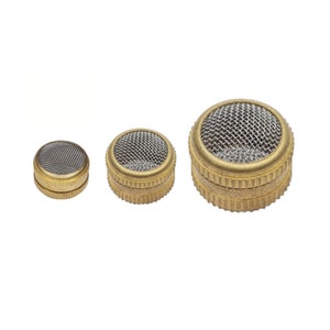 May include: Three brass mesh strainers of varying sizes are arranged on a white background. Each strainer has a fine metal mesh screen set within a brass housing. The brass has a slightly aged appearance.