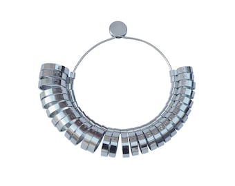 May include: A silver ring sizer with a circular metal frame and a series of numbered rings. The rings are arranged in a circle, with the largest ring at the top and the smallest ring at the bottom.