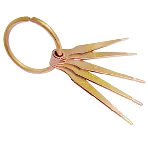 May include: A set of gold-colored jeweler's gauges, attached to a circular ring. Each gauge has a pointed end and is marked with a measurement. The gauges are arranged in a fan-like pattern.