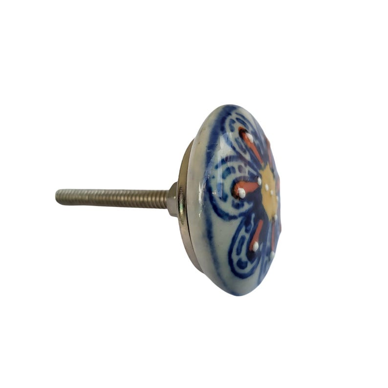 May include: A decorative ceramic cabinet knob with a floral design. The knob features a white base with a blue floral pattern, accented with orange and yellow details. It has a metal screw for installation.