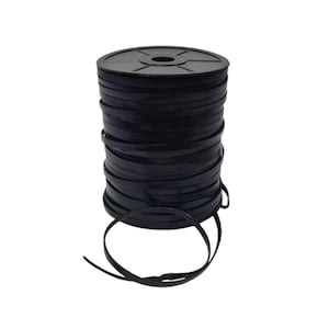 Op de afbeelding: Een spoel zwart plat lint. Het lint is strak op een zwarte plastic kern gewikkeld. Een lengte van het lint strekt zich uit van de spoel en vormt een lus. Het lint lijkt gemaakt van een flexibel, mogelijk synthetisch materiaal.