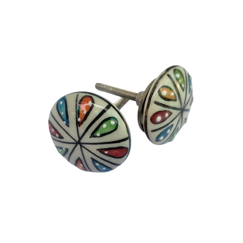 May include: Two decorative ceramic cabinet knobs. Each knob has a white background with a colorful, stylized floral design in red, blue, green, and orange. The knobs are mounted on silver-colored screws.