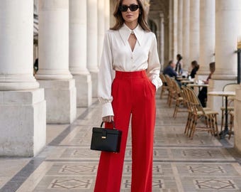 May include: A white ceramic mug with a black handle and the text "But First, Coffee" in a bold, black font. The mug is set against a blurred background, suggesting a cozy setting.