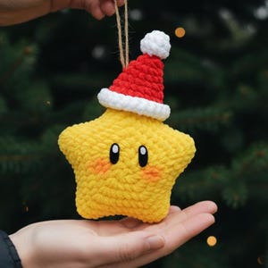 Puede incluir: Adorno de estrella amarilla tejida a ganchillo con un gorro de Papá Noel rojo y blanco. La estrella tiene ojos negros y mejillas rosadas. Se adjunta una cuerda marrón para colgar. Decoración festiva para Navidad.