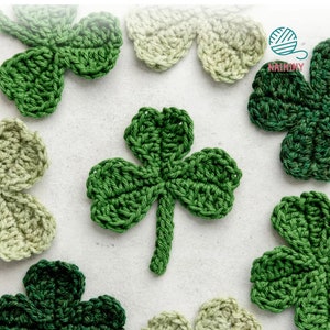 Puede incluir: Una colección de tréboles de ganchillo verde y verde claro sobre un fondo blanco.