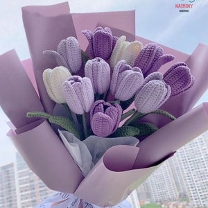 May include: A bouquet of crocheted purple and white tulips wrapped in lavender paper with a white ribbon that says "Romantic" in cursive.