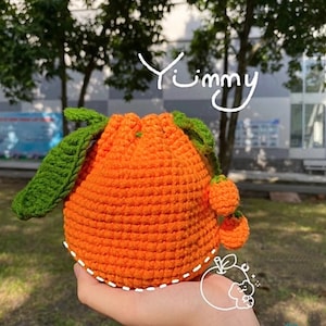 May include: A crocheted orange with green leaves and small orange accents. The orange is a drawstring bag with the word "Yummy" written above it.