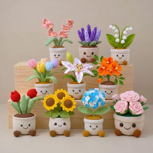 May include: A collection of eleven crocheted potted plants, each featuring a beige pot with a stitched smiling face and small brown feet. The plants include various colorful flowers like pink, purple, orange, yellow, blue, and white blossoms.