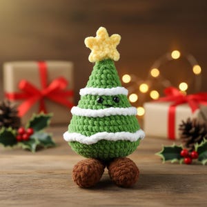 May include: A handmade green crochet Christmas tree with white trim and a yellow star on top. The tree has a smiling face and sits on two brown crochet balls. The background includes wrapped gifts and Christmas lights.