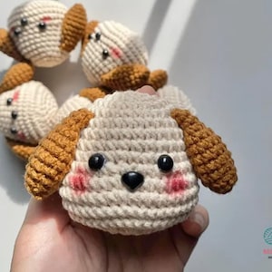 Peut inclure: Un ensemble de peluches de chien en crochet avec des oreilles brunes et des corps blancs. Les peluches ont des yeux noirs et un nez noir.