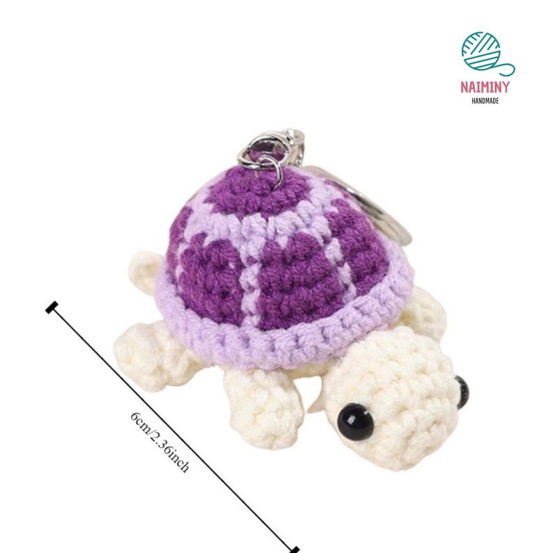 Op de afbeelding: Een gehaakte schildpad sleutelhanger met een paarse en witte schil. De schildpad is ongeveer 6 cm of 2,36 inch hoog.