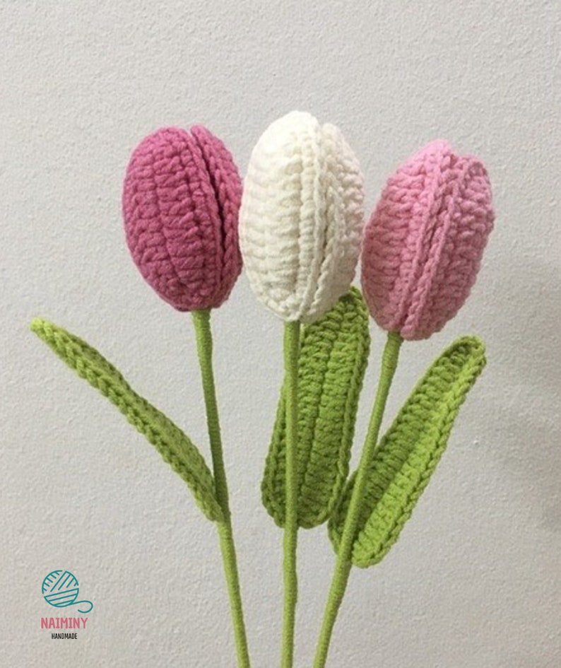 May include: Three crocheted tulips in pink, white, and light pink with green crocheted stems and leaves.