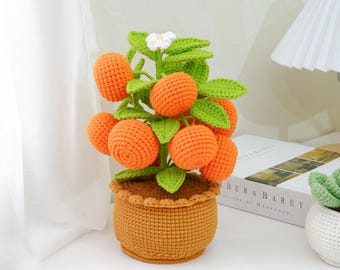 May include: A handcrafted crochet orange tree with bright orange fruit, green leaves, and a small white flower. The tree is planted in a brown crochet pot. The decorative tree is a unique home decor item.
