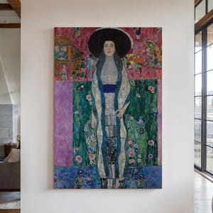 May include: A rectangular canvas painting featuring a portrait of a person wearing a wide-brimmed black hat and a patterned robe. The artwork displays a vibrant color palette of pink, green, and blue, with intricate decorative details throughout.