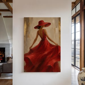 May include: A vertical wall art painting depicting a figure from behind wearing a wide-brimmed red hat and a flowing red dress. The figure is positioned against a neutral, textured background with vertical gold leaf accents on the left and right sides.