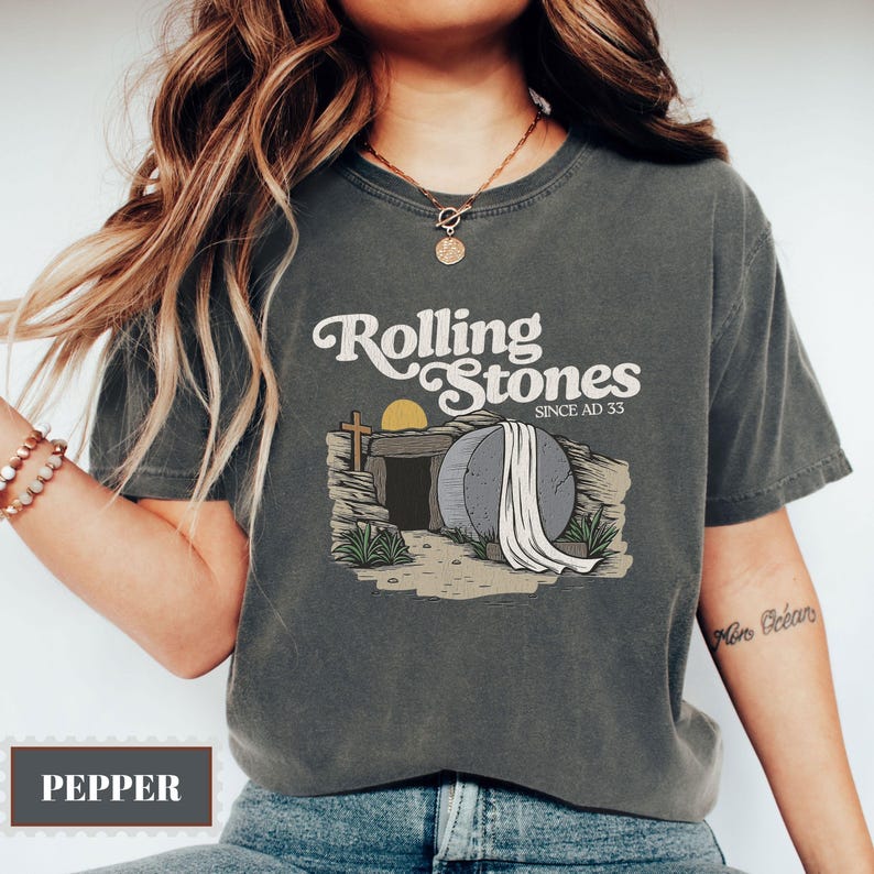May include: A gray t-shirt with a vintage-style graphic of a stone tomb with a white sheet draped over it. The text "Rolling Stones Since AD 33" is above the tomb.
